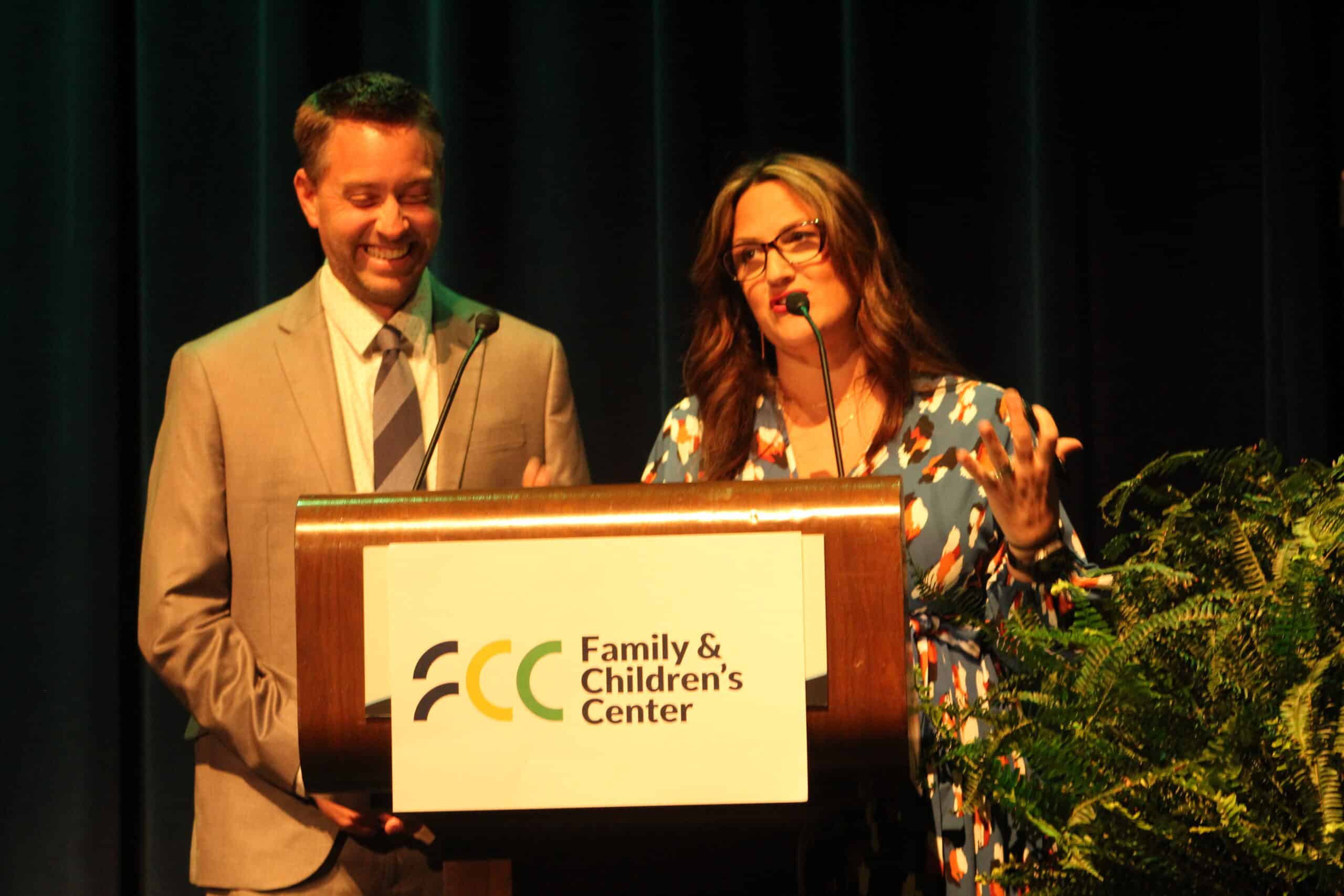 Jennifer Livingston speaks at podium while Mike Thompson laughs
