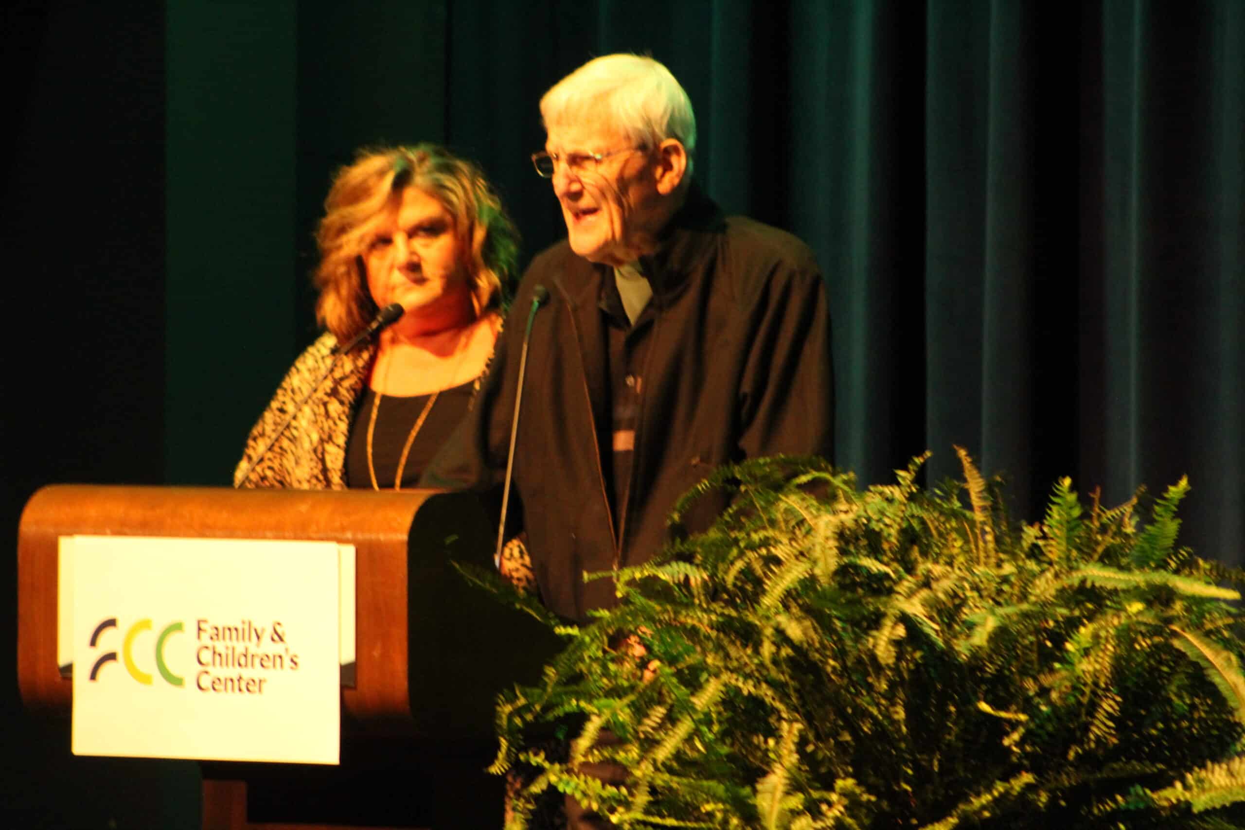 Jerry Papenfuss speaks at podium while Andrea Wieser looks on.